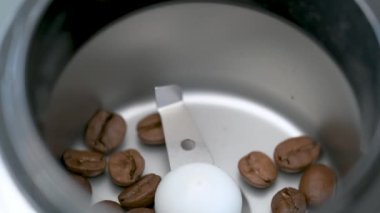 Pouring coffee beans into a grinder to prepare coffee.