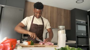 Genç Afrikalı bir adam mutfakta yemek tarifi hazırlamak için tavukları kemikten arındırıyor..