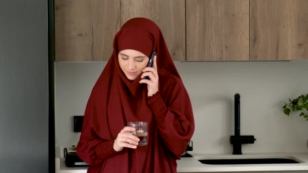 Muslim Young Woman Hijab Drinking Water Talking Smartphone Kitchen Home — Stockvideo