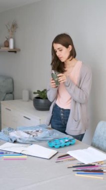 Caucasian woman taking a photo of her art design in a denim jacket. Unique clothing designs.