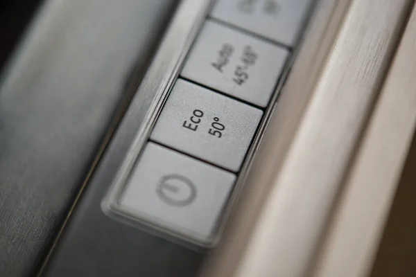 Close-up of eco button in a modern dishwasher control panel. Eco-friendly and energy-efficient household appliances.