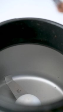 Pouring coffee beans into a grinder to prepare coffee.