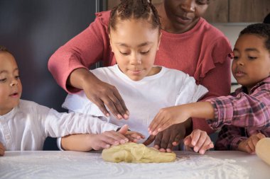 African family kneading cookie dough in the kitchen. Horizontal extended family.
