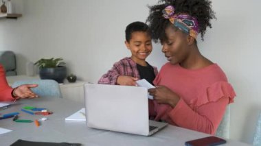 Son giving her mother a picture he has drawn for mothers day present. Happy african family.
