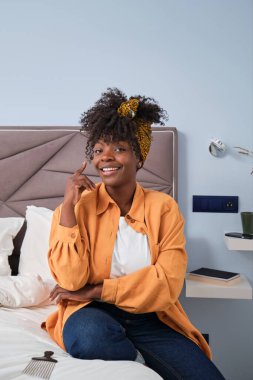 Portrait of african young woman looking at camera and smiling in her bedroom.