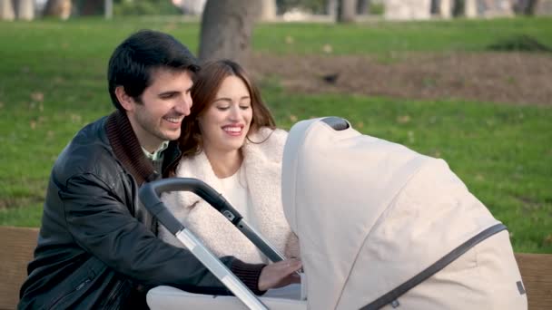 Para Rozmawiająca Swoim Dzieckiem Wózku Całująca Się Przytulająca Siedząc Ławce — Wideo stockowe