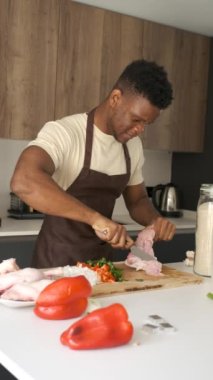 Genç Afrikalı bir adam mutfakta yemek tarifi hazırlamak için tavukları kemikten arındırıyor..