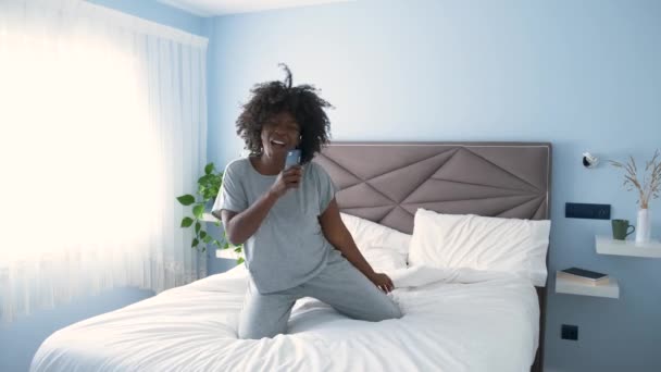 Smiling African Young Woman Wearing Pajama Dancing Favorite Music Bed — Video Stock