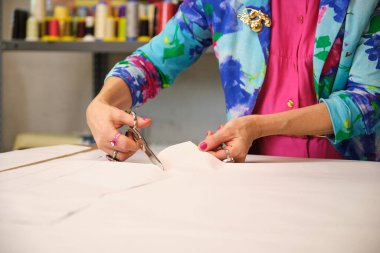 Renkli kıyafetler giyen terzinin kapatılması dikiş atölyesinde dikiş desenleri kesilmesi.