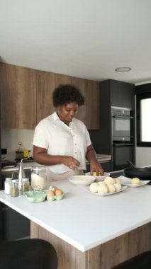 Kübalı mutlu genç kadın Küba usulü doldurulmuş patatesleri hazırlamak için dans ederken patates püresi yapıyor..