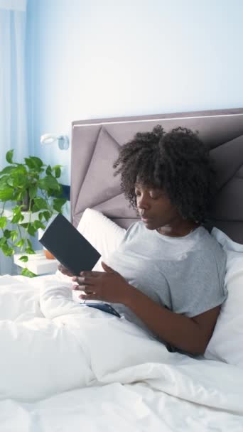 アフリカの若い女性が本を読んでいる間誰かがベッドの上で彼女を呼び出します — ストック動画