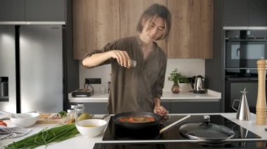 Asyalı genç adam Çin ya da Tayvan domatesli yumurta pişirmek için baharat ekliyor..
