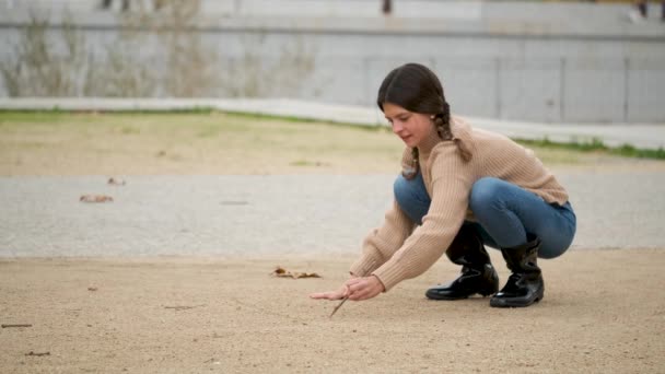 Mädchen Mit Zwei Zöpfen Zeichnet Hopscotch Sand Mit Einem Stock — Stockvideo