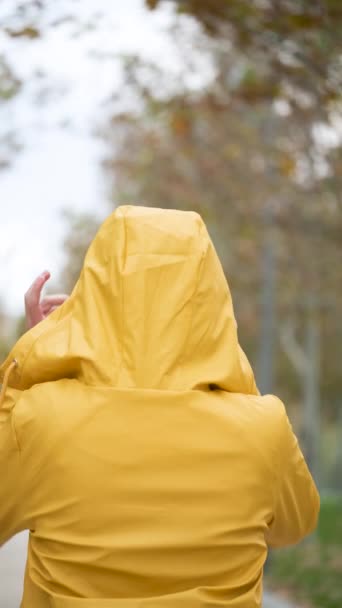 穿着黄色雨衣的少女在户外转身微笑的画像 — 图库视频影像