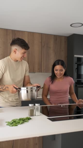 2人の若いラテン人が調理法を準備するために誘導調理器をオンにキッチンで — ストック動画
