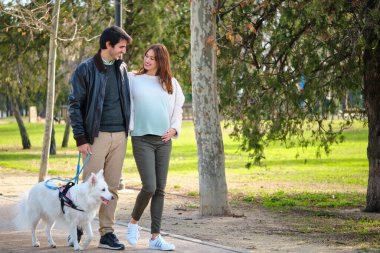 Erkek ve hamile kadın köpekleriyle parkta yürüyorlar. Aile.