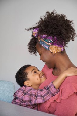 Gülümseyen Afrikalı anne ve oğlu evde sarılıyorlar..