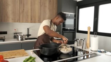 Genç Afrikalı adam mutfakta sebzeli kızarmış tavuk kıyması hazırlıyor..