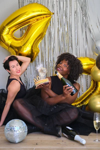 在一个40岁生日聚会上 两个多种族女人笑着喝着香槟酒 吃着蛋糕 — 图库照片