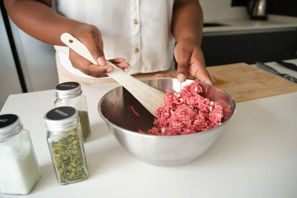 Close up of cuban woman hands mixing raw minced beef and garlic to prepare cuban style stuffed potatoes.