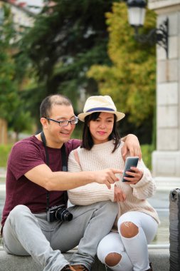 Çok ırklı iki turist akıllı telefonlarıyla şehir rehberine danışıyor. Madrid, İspanya 'yı gezmek.