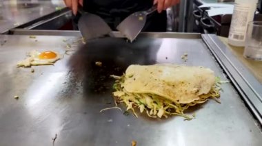 Yerel Hiroşima restoranında okonomiyaki pişiriyorum. Video 4. Soslu şehriye ve tabanda kırık yumurta ekliyorum..