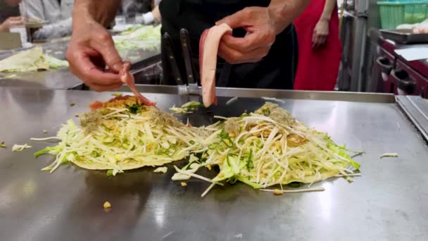 広島の郷土料理店でお好み焼きを作る ビデオ3 豚の腹肉の追加 — ストック動画