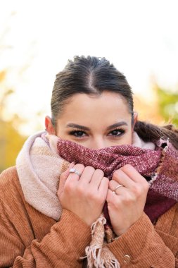 Soğuk bir sonbahar boyunca beyaz bir kadın atkıyla boynunu ısıtıyor..