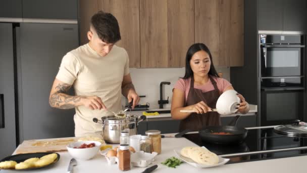 2人の若いラテン人が台所で一緒に調理する — ストック動画
