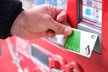 Kyoto, Japan. April 18, 2023: Close up of a hand paying with suica card to get a drink in a japanese vending machine, jidouhanbaiki. clipart