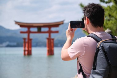 Itsukushima Jinja Otorii 'nin fotoğraflarını çeken Avrupalı turist veya Miyajima, Hiroşima, Japonya' daki Grand Torii Kapısı.