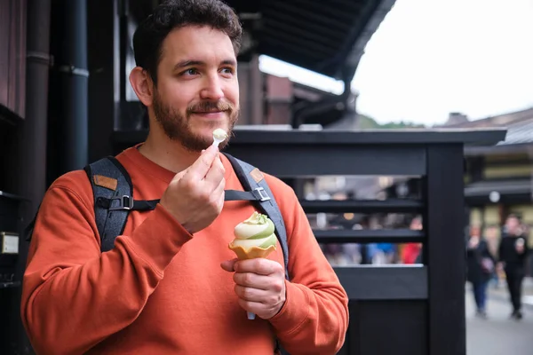 stock image European tourist eating matcha ice cream standing at street outside of a kiosk in Takayama town, Hida, Gifu, Japan.