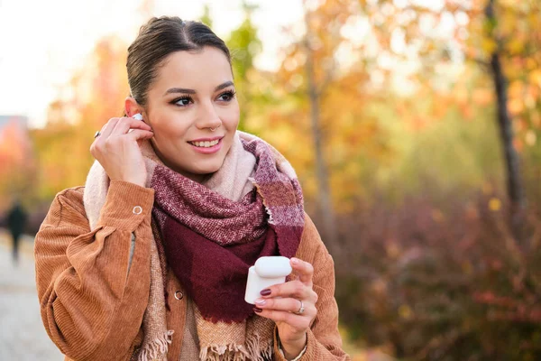 stock image Caucasian young woman wearing earphones smiling in autumn.