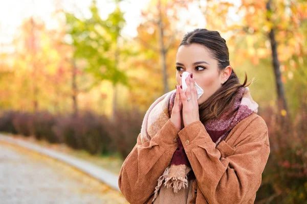 秋に鼻を組織に吹き込む白人の若い女性 — ストック写真