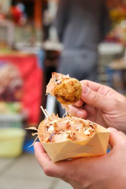 Japonya 'da bir Takoyaki teknesi sokak yemeği tutan eller..