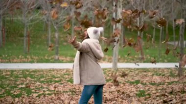 Sonbahar yaprakları sonbahar mevsiminde onun üzerine düşerken küçük kız döner oynuyor. Mutluluk.