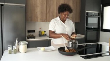 Kübalı genç bir kadın Küba usulü doldurulmuş patatesleri hazırlamak için patates püresi yapıyor..