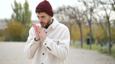 Latin genç adam ellerini ovuşturuyor, öksürüyor ve kış boyunca burnu dokulara sümkürüyor. Soğuk hava. Grip..