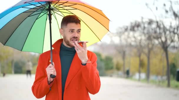 Latin Ung Man Med Röd Rock Och Regnbåge Paraply Inspelning — Stockvideo