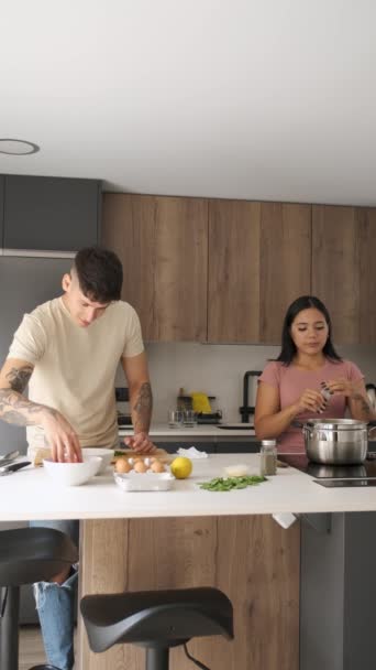 ガロを準備する2人の若いラテン人と台所でレシピを準備するために鍋に塩を追加 — ストック動画