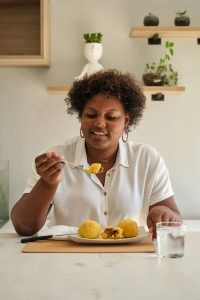 stock image Young cuban woman eating homemade cuban style stuffed potatoes and drinking water.