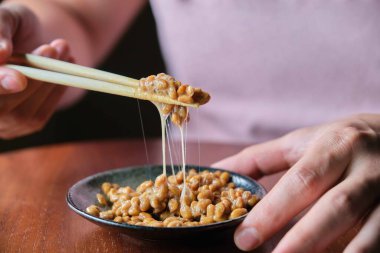Yemek çubuğuyla mayalanmış soya fasulyesi yiyen tanınmamış bir adam. Japon geleneksel yemekleri.