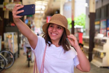 İspanyol bayan turist Japonya 'nın Osaka kentindeki Dotonbori' deki kapalı Japon pazarında selfie çekiyor..