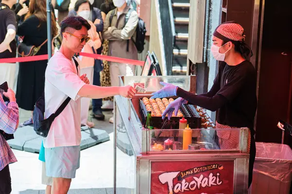 24 Mayıs 2023 'te Japonya' nın Osaka şehrinde, takoyaki, ahtapot topları alan adam,.