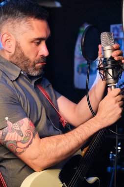 Şarkıcı ve gitarist stüdyoda şarkı kaydetmeden önce mikrofonu ayarlıyorlar..