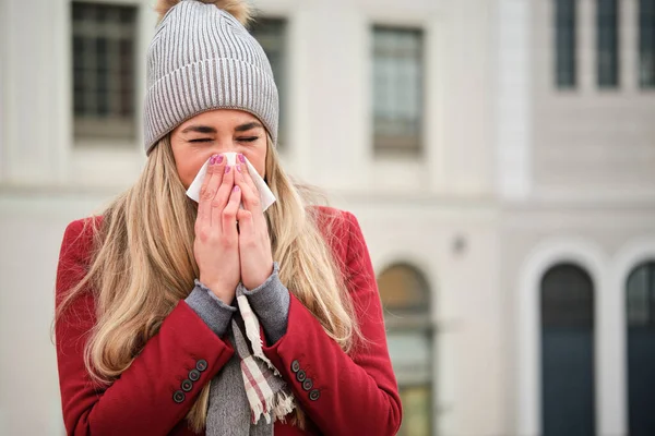 白人の若いブロンドの女性は冬の間に組織に鼻を吹いていた 寒い天気 — ストック写真