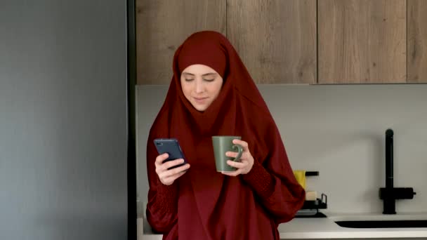 Muslim Young Woman Hijab Drinking Coffee Using Smartphone Kitchen Home — Vídeos de Stock