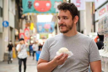 Japonya 'nın Osaka kentindeki Dotonbori caddesinde nikuman yiyen Latin turist..