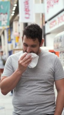Latin genç adam nikuman yiyor ve Japonya 'nın Osaka kentindeki Dotonbori caddesindeki kameraya bakıyor..