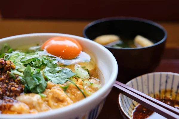 Oyakodon seti, üzerinde tavuk ve yumurta olan bir kase pirinç, ve kitsune tofu ile miso çorbası ve bir restoranda wakame yosunu..